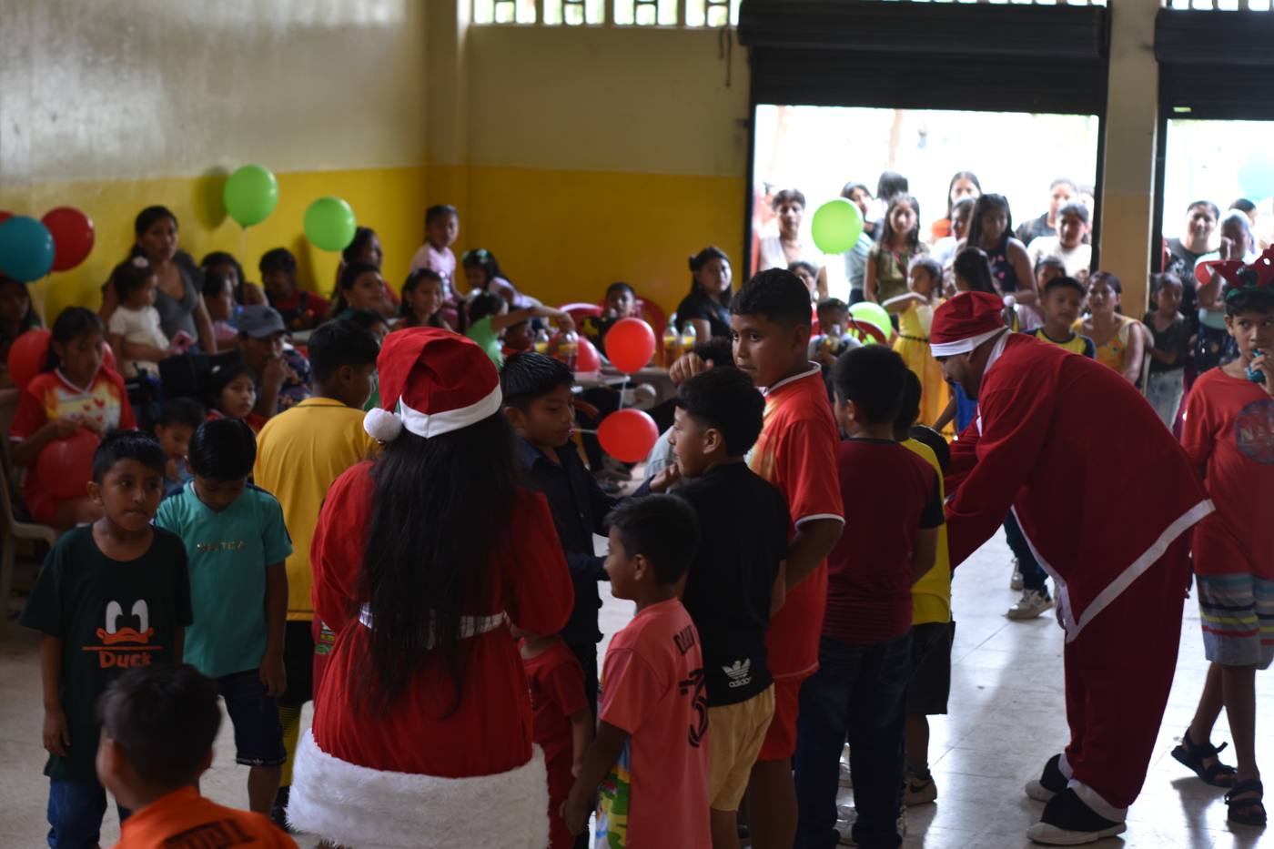 Voluntarios vestidos de Papá Noel con niñas y niños en la fiesta navideña